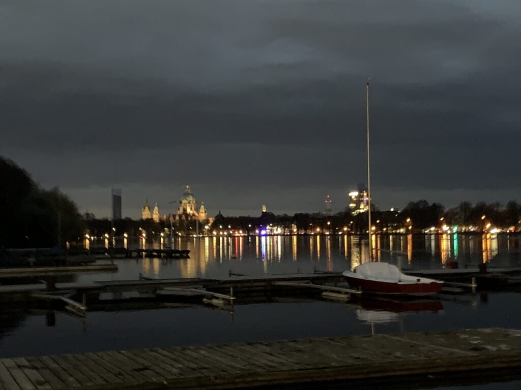 Blick bei Dunkelheit vom Bootshaus auf den Maschsee mit dem Rathaus.